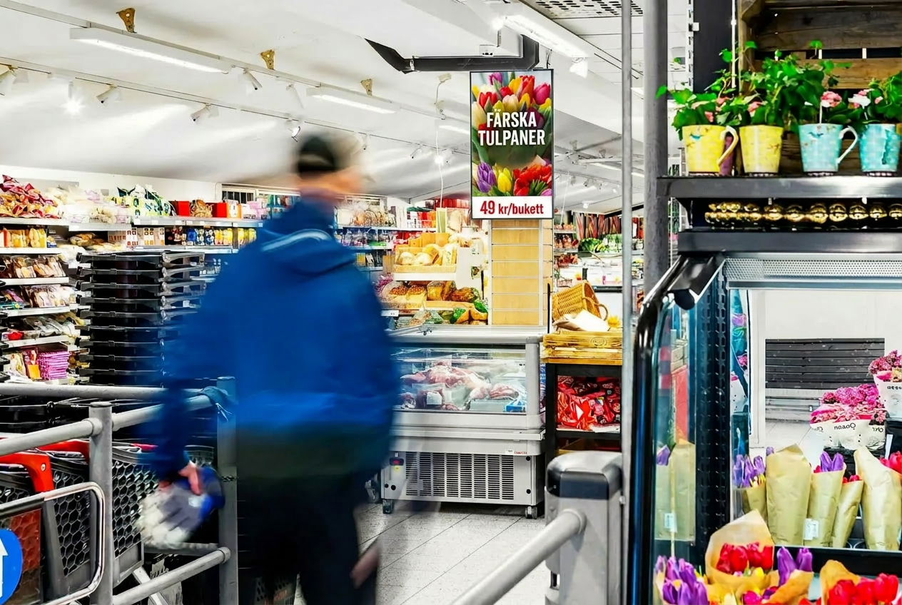 Digital annonsskärm vid entrén i en Hemköp-butik med annons för färska tulpaner
